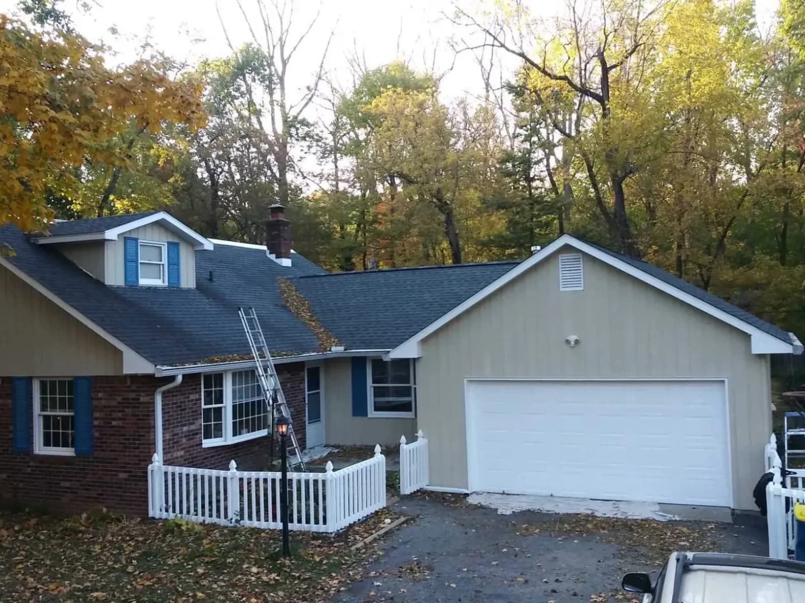 Siding repainted tan with blue shutters on a brick ranch